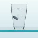 Ein Wasserglas mit auflösender Brausetablette vor hellem Hintergrund.